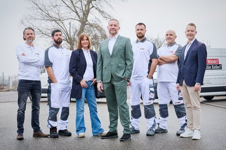 ISOTEC Team steht vor Firmenfahrzeugen auf Parkplatz, Gruppenporträt im Freien